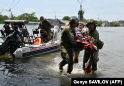 Украинские военнослужащие эвакуируют местных жителей из затопленной зоны в Херсоне после прорыва Каховской ГЭС, 8 июня 2023 года, фото AFP