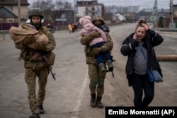 Украинские военные несут детей, помогая эвакуироваться бегущей от войны семье. Окраина Киева, 5 марта 2022 года.