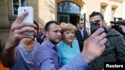 Almaniya kansleri Angela Merkel 2015-ci ildə Berlində qaçqınlarla selfi çəkdirərkən