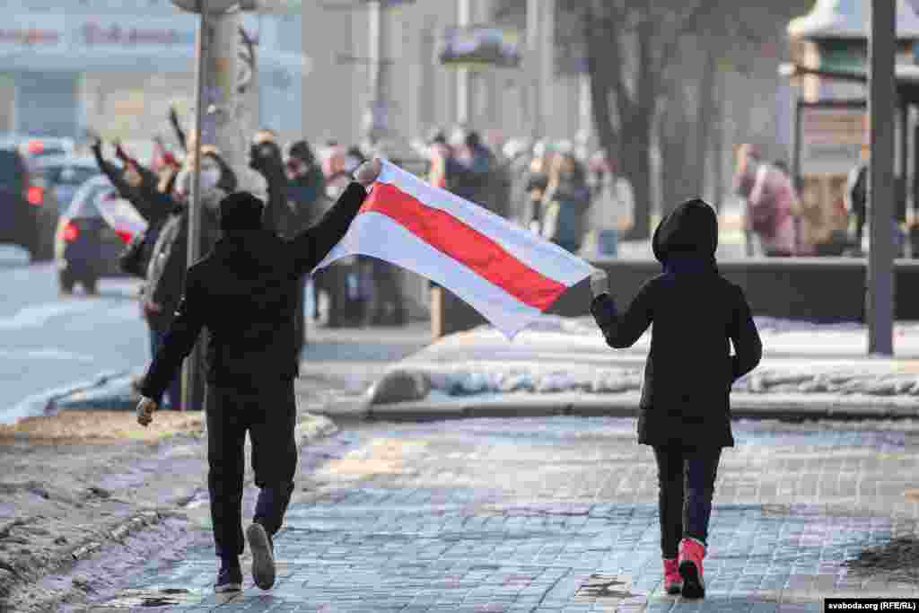 Людзі нясуць сьцяг каля парку Чалюскінцаў.