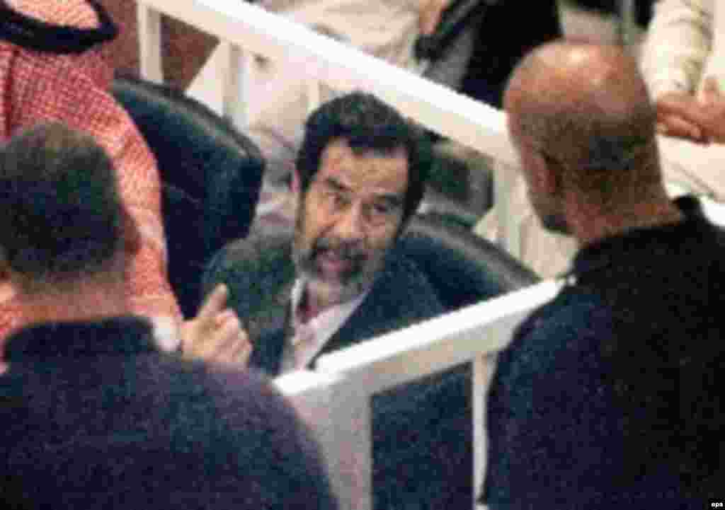 Saddam Hussein in court cell, 19 October 2005, talking to guards maybe. first day of trial in Baghdad.