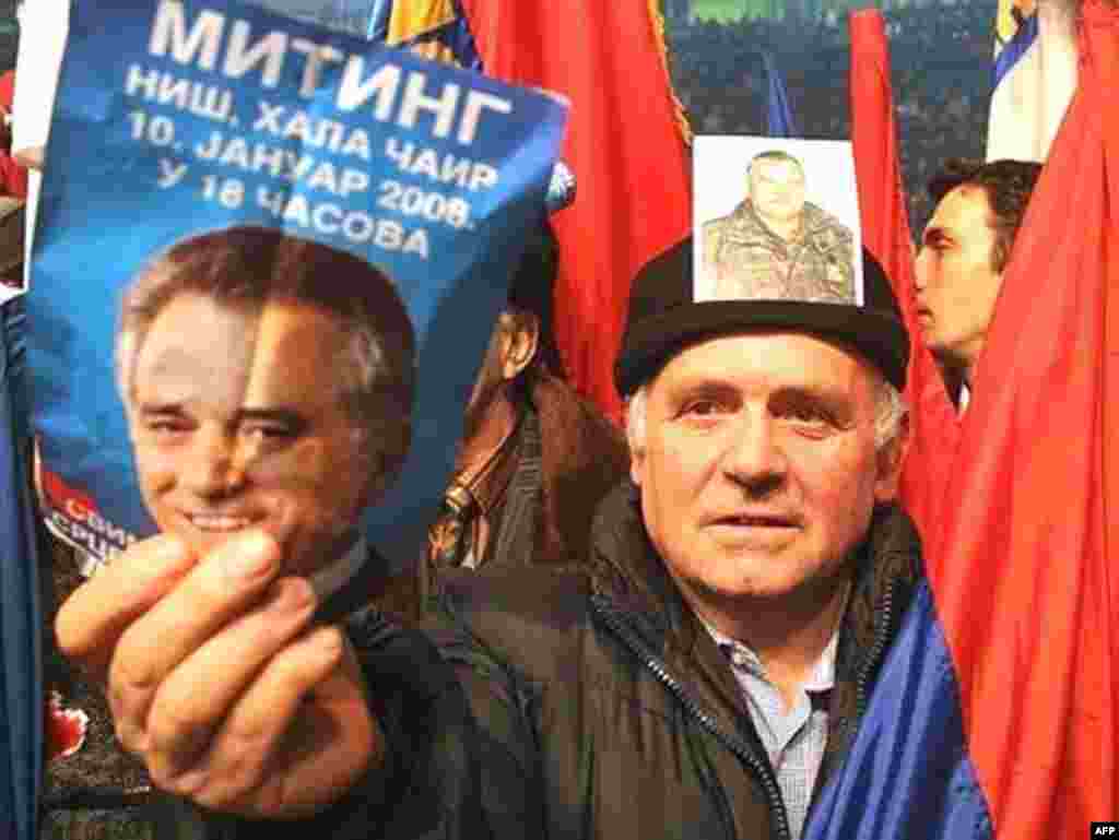 A supporter of Serbian Radical Party carries pictures of his party leader Tomislav Nikolic (L) and Bosnian Serb army commander and most wanted war crimes fugitive General Ratko Mladic (R) during a pre-election rally in Nis, 10 January 2008.