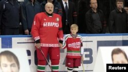 Belarus -- President Alyaksandr Lukashenka and his son Nikolay stand behind portraits of Marat Kalimullin (L) and Ruslan Salei during a commemorative event at the Minsk-Arena sports complex in Minsk.