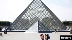 FRANCE - FILE PHOTO: Tourists stand in front of the Louvre Pyramid designed by Chinese-born U.S. Architect Ieoh Ming Pei in Paris, France, September 13, 2016