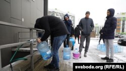 Валянтэры набіраюць ваду ў будынку, дзе яна ёсьць, каб прывезьці туды, дзе яе адключылі