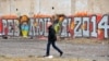 Ukraine -- A man walks past a graffito reading "Revolution 2014" on a building in central Kyiv, February 17, 2014